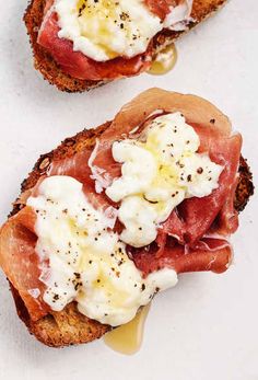 two pieces of bread with meat and cheese on them sitting next to each other,