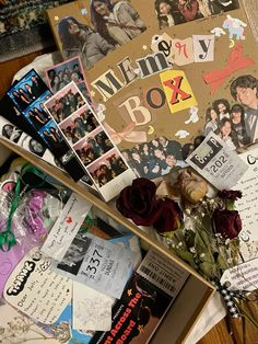 a box filled with pictures and flowers on top of a wooden table next to other items