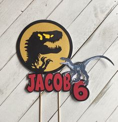 a dinosaur cake topper with the name jacob 6 on it and a t - rex