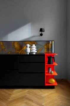 a black and red cabinet with vases on it in a room that has wood flooring