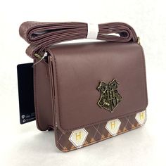 Harry Potter Hogwarts Crest Argyle Crossbody Bag Purse Faux Leather Adjustable Carry your class essentials around Hogwarts in style! This Harry Potter crossbody bag is perfect for holding your quill and a bit of parchment. It features a "H" and brown argyle print and the Hogwarts crest embossed on the front flap. Complete with adjustable crossbody strap, interior drop pocket and snap-button closure. 7'' x 3 1/2'' x 6'' Polyurethane Adjustable strap Magnetic snap-button closure Interior drop pocket Brand New! Harry Potter Purse, Granger Aesthetic, Hermione Granger Aesthetic, Harry Potter Bag, Harry Potter Accessories, Harry Potter Merch, Harry Potter Items, Cute Harry Potter, Cozy Life