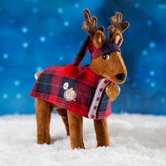 a stuffed reindeer wearing a red and black plaid coat in the snow with blue background