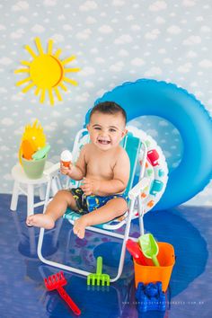 a young boy sitting in a lawn chair with toys around him and smiling at the camera