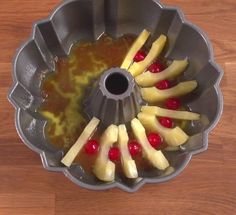 a bundt cake pan with apples and bananas in it on a wooden table top