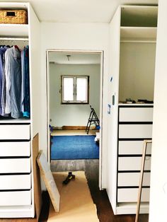 an empty room with some drawers and clothes hanging on the wall in front of it