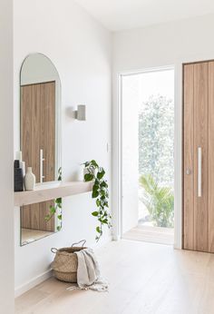 a white room with wooden doors and a large mirror on the wall, next to a plant in a basket