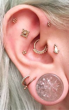 an ear with several piercings on it and a coin sitting next to the ear