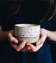 a person holding a white bowl in their hands with dirt all over it and black background