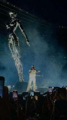 a man standing on top of a stage next to a giant human figure in the air