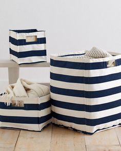 blue and white striped storage bins sitting on top of a wooden floor next to a bench