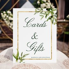 a card that says cards and gifts on it with greenery around the edges, sitting on top of a table