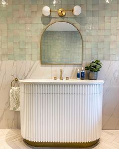 a white bath tub sitting next to a mirror on top of a tiled bathroom wall