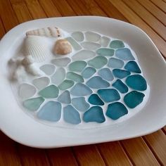 there is a white plate with sea glass on it