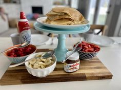 a plate with some food on it next to bowls of fruit and condiments