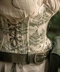 a corset with green leaves on it is seen in this image from the waist up