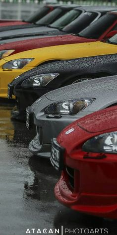 a row of parked cars sitting on top of a wet parking lot next to each other