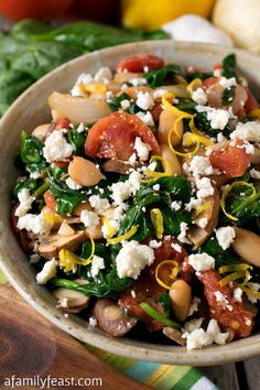 a close up of a bowl of food with spinach and other foods in the background