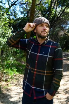 a man is standing in the woods wearing a hat and looking off into the distance