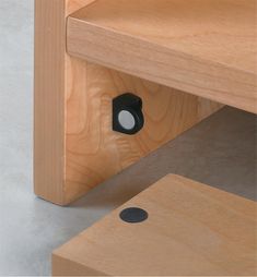 a close up of a wooden shelf with a hole in the middle and a black dot at the bottom