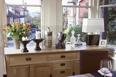 a dining room table with vases and flowers on it next to a large window