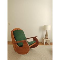 a wooden rocking chair sitting on top of a carpeted floor next to a white wall