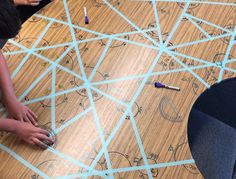 two children are drawing on the floor with colored pencils and crayon tape