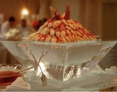 a large bowl filled with lots of food on top of a glass table covered in silver foil