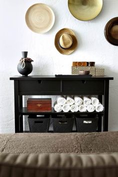 there is a black table with many hats on the wall above it and baskets below