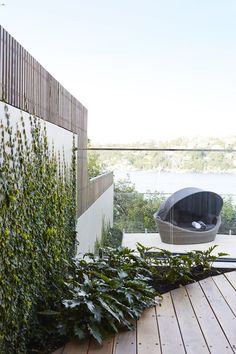 an outdoor area with wooden floors, plants and a bench on the side of it