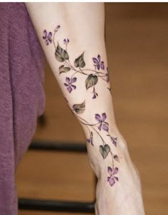 a woman's foot with purple flowers on it