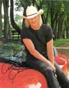 a man sitting on top of a red car wearing a cowboy hat and black shirt