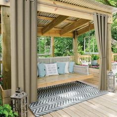 a wooden bench sitting under a pergoline covered gazebo with blue and white pillows