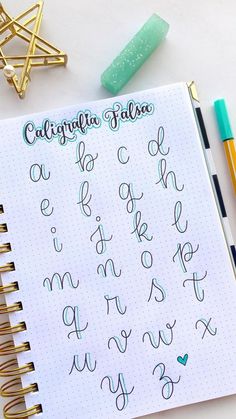 a notebook with cursive writing on it next to some pens and pencils