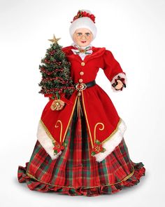 a christmas doll is dressed in red and green, with a tree on her lap