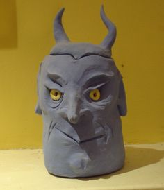 a blue mask with yellow eyes and horns on top of a shelf next to a wall