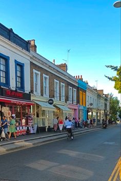 people are walking down the street in front of stores and shops on either side of the road