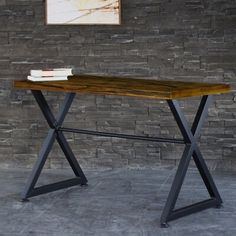 a wooden table sitting in front of a brick wall with two books on top of it