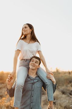 a man carrying a woman on his back in the middle of an open field at sunset