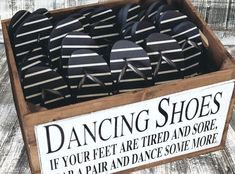 a box filled with black and white striped shoes on top of a wooden table next to a sign that says dancing shoes if your feet are tired and sore