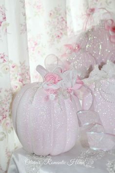 pink pumpkins are sitting on a table in front of floral wallpaper and curtains