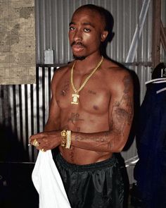 a man with no shirt on holding a white towel in his hand and wearing gold jewelry