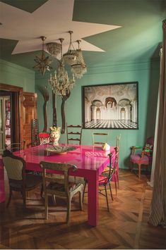 a dining room with green walls and pink table cloths on the wooden flooring