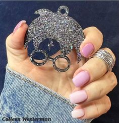 a woman with pink nails holding up a glittered object