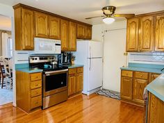 a kitchen with wooden cabinets and blue counter tops, white appliances and wood flooring