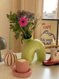 a vase with flowers in it sitting on a table next to a cup and saucer