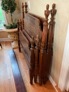 a wooden bed frame sitting on top of a hard wood floor next to a window