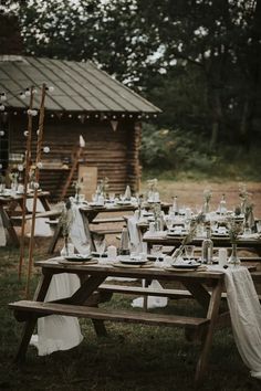 an outdoor table set up with white linens and greenery for a rustic wedding