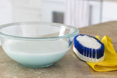 a blue and white brush sitting on top of a counter next to a glass bowl