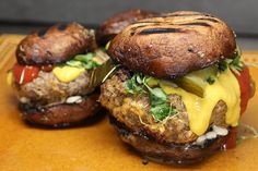 two hamburgers sitting on top of a wooden cutting board