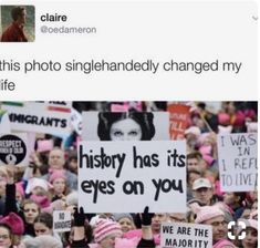 a group of people holding up signs in the middle of a crowd with pink hats